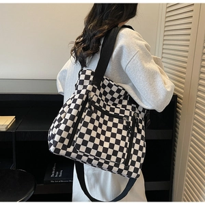Detail of checkered tote bag showing dual zipper pockets and wide shoulder strap
