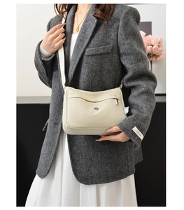 Detail of off-white nylon crossbody bag on model featuring front zipper and adjustable strap