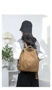 Brown nylon backpack worn by a model in a minimalist setting showing daily casual style