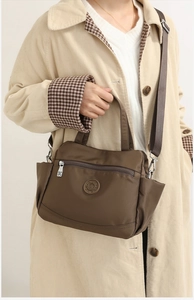 Detail of dark brown nylon multi-pocket shoulder bag shown on a model's arm