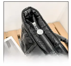Close-up of smooth silver metal zipper on black quilted puffer tote bag detail