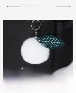 Dettaglio dello zaino oxford nero con pompon bianco e ciondolo a forma di foglia verde