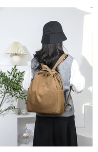 Detail of water-resistant nylon backpack showing side zipper pocket and metal logo