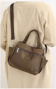Macro shot of dark brown nylon shoulder bag with zipper detail and embossed logo