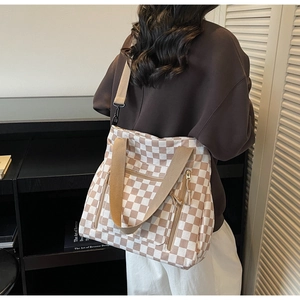 Detail of checkered tote bag showing multi-zipper pockets and large canvas texture
