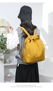 Close-up of ginger yellow water-resistant nylon backpack worn on a model's back