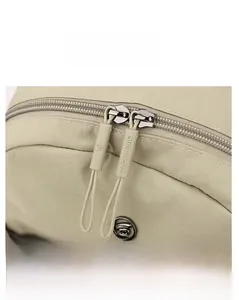 Detailed macro view of high-quality metal zippers and textured nylon fabric on the beige backpack
