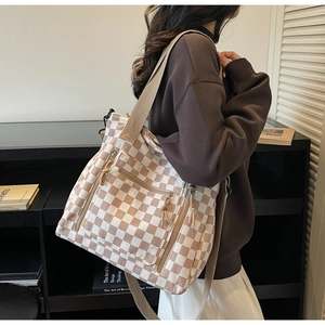 Detail of checkered canvas tote bag showing multiple zipper pockets and side capacity