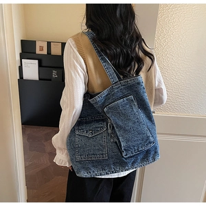 Detail of blue denim tote bag with functional pockets and stylish washed texture