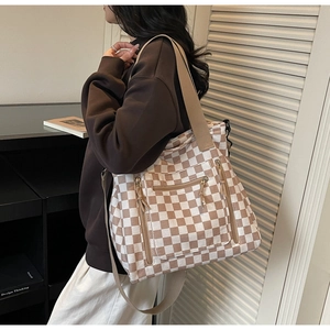 Detail of checkered tote bag with multiple zipper pockets and wide fabric shoulder strap