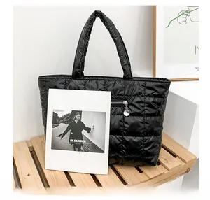 Detail of black quilted tote bag with square stitching and silver metal zipper on front pocket
