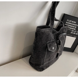 Detail of dark grey denim tote bag with functional pockets and white contrast stitching