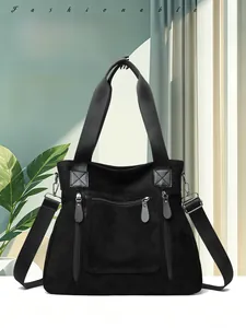Detail of black suede tote bag showing functional zippers and adjustable shoulder strap