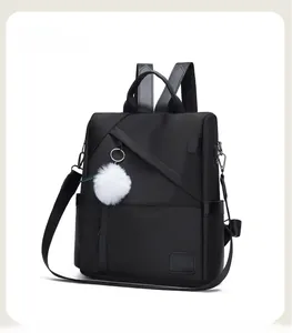 Detail of black waterproof Oxford cloth backpack with side pockets and white fur ball charm