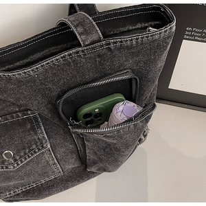 Close-up of denim tote bag with multi-pocket storage and white contrast stitching