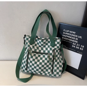 Detail of green checkerboard tote bag with multiple zip pockets and adjustable shoulder strap