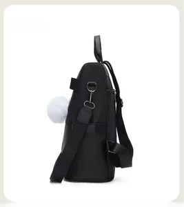 Side view of black Oxford cloth backpack with plush ball charm and sturdy handle