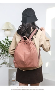 Rear view of a model wearing a water-resistant mauve nylon backpack with logo detail