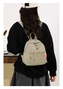 Detailed back view of a beige nylon mini backpack with logo on a female model