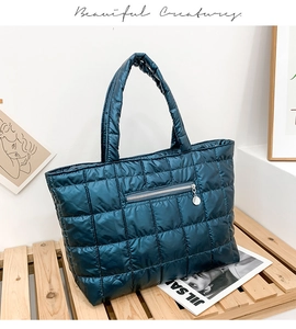 Macro detail of glossy peacock blue quilted puffer tote bag with round metal zipper