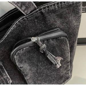 Detailed macro view of dark grey denim tote bag featuring white contrast stitching and zip pocket