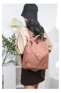 Detail of water-resistant nylon backpack in dusty rose pink worn by a model in a cozy setting