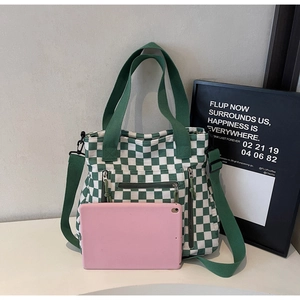 Checkered green and white tote bag detail with three front zippers and tablet for scale