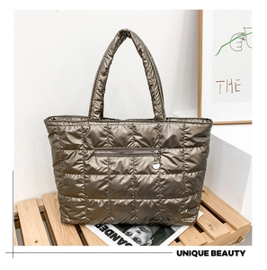 Macro shot of bronze quilted tote bag featuring metallic zipper pocket and diamond pattern