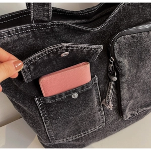 Detail of dark grey denim tote bag with white stitching and front utility pockets