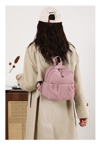 Detailed close-up of pink mini nylon backpack with ruched design and red side logo label