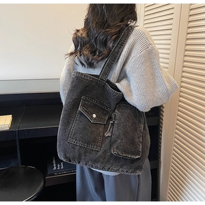 Detail of dark denim tote bag featuring utility pocket and small detachable side pouch