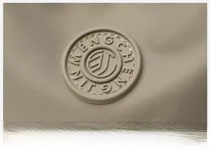 Close-up of khaki nylon fabric texture and circular rubber logo on the shoulder bag