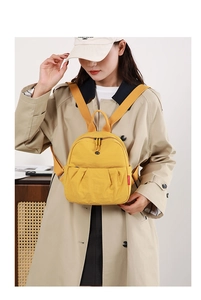 Detail of yellow mini canvas backpack with pleated pocket design and metal zipper closure