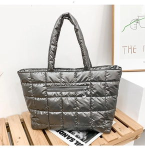Detail of quilted metallic grey puffer tote bag with zipper pocket and metal ring puller