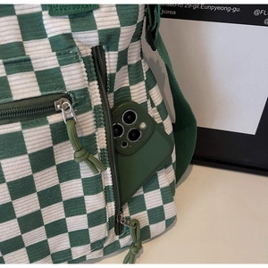 Close-up of green checkerboard corduroy tote bag showing large capacity pocket for smartphone