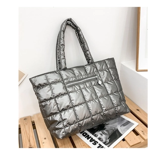 Detail of silver quilted tote bag with metallic finish and front zipper pocket