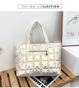 Detail view of champagne quilted down tote bag with a front zip pocket and soft texture