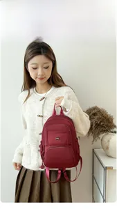 Deep red waterproof nylon travel backpack with multiple compartments shown on model