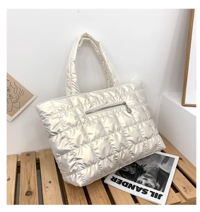 Detail of champagne quilted puffer tote bag with front zip pocket and high-gloss finish