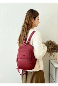 Model wearing a wine red multifunctional nylon backpack with zippers and metal logo