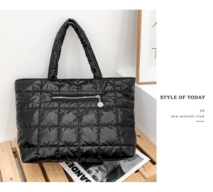 Detail of black quilted tote bag featuring a front zipper pocket and padded texture