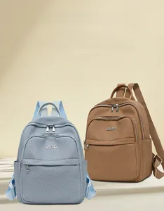 Détail de la texture tissée et logo métallique sur sacs à dos de voyage en nylon bleus et bruns