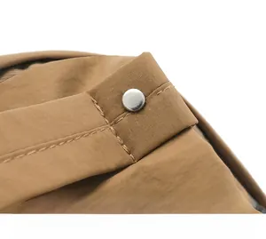Detailed close-up of brown nylon backpack with silver rivet reinforcement and durable stitching