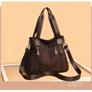 Detailed view of dark brown suede tote bag featuring three front zipper pockets
