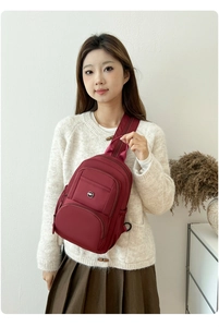 Close-up of burgundy waterproof nylon crossbody bag with multi-zipper storage compartments