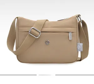 Detail of khaki waterproof nylon crossbody bag with metal logo and adjustable strap