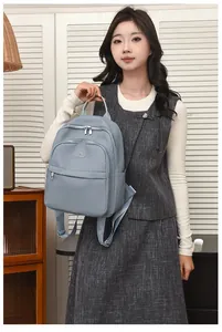 Détail du sac à dos en nylon bleu clair avec plusieurs poches zippées et logo en métal