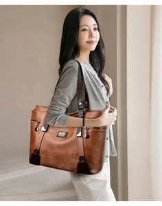 Vue détaillée du cuir grainé marron et de la plaque métallique sur un sac fourre-tout chic