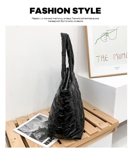 Detail of black quilted tote bag with glossy puffer material and soft padded texture