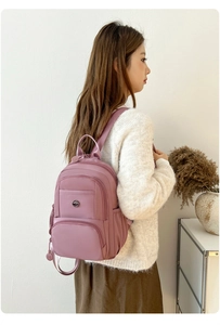 Close-up of lotus pink nylon backpack with adjustable straps on a person's shoulder